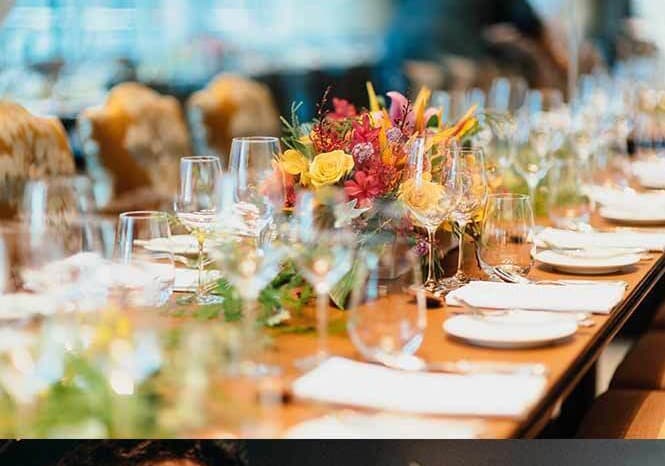 A long dinner table with fresh flowers and glassware